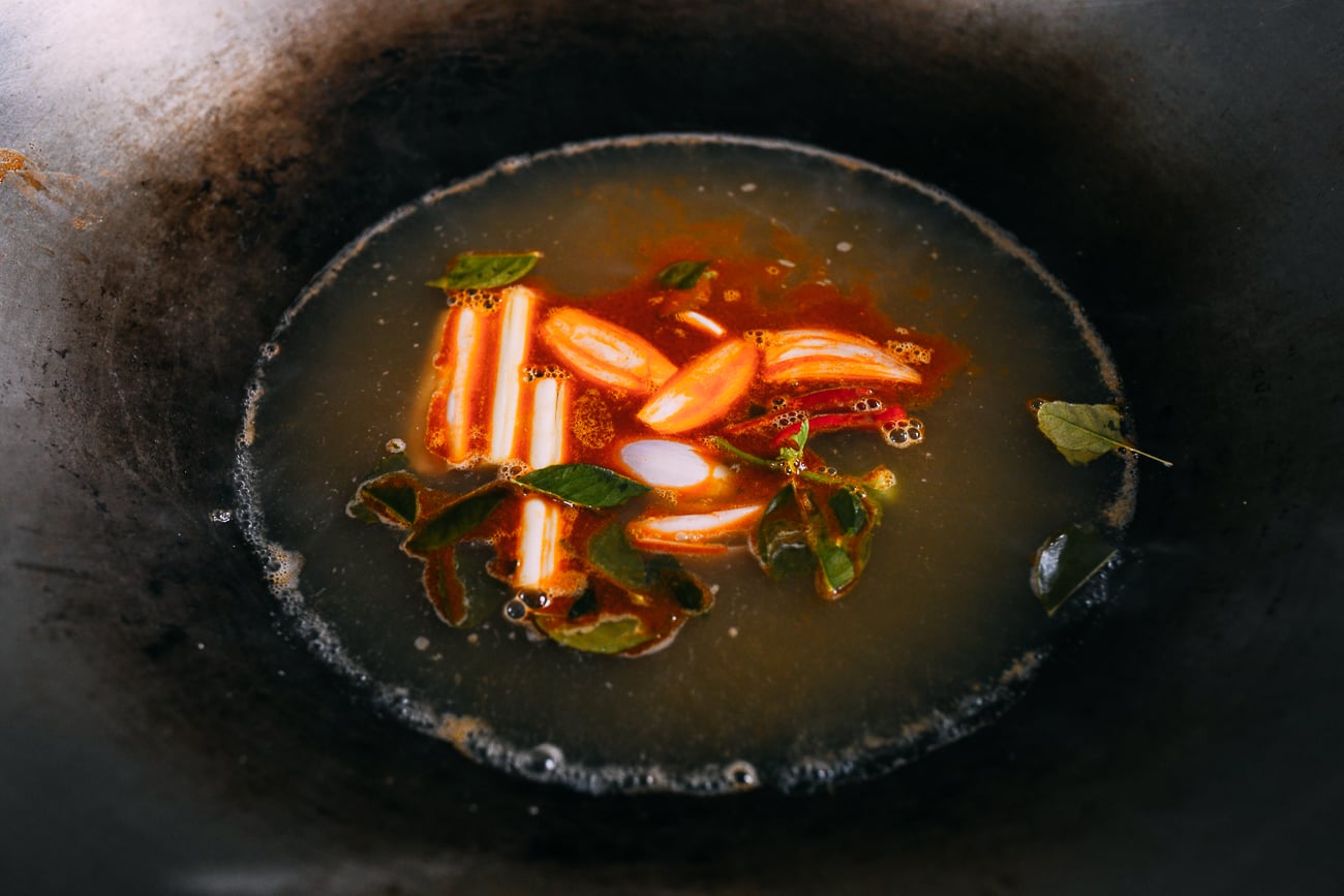 Lemongrass, lime leaves, chilies, shallots, galangal, and cilantro stem in broth