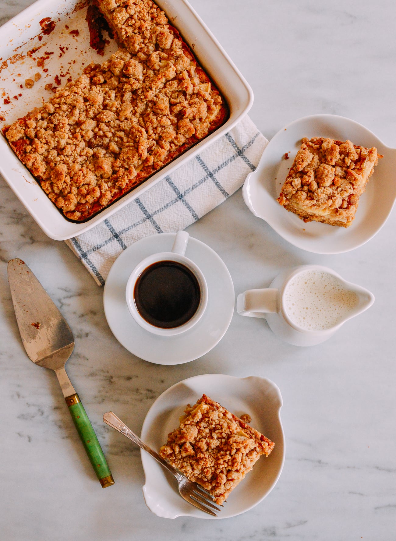 Sliced apple cinnamon coffee cake with cake server and coffee