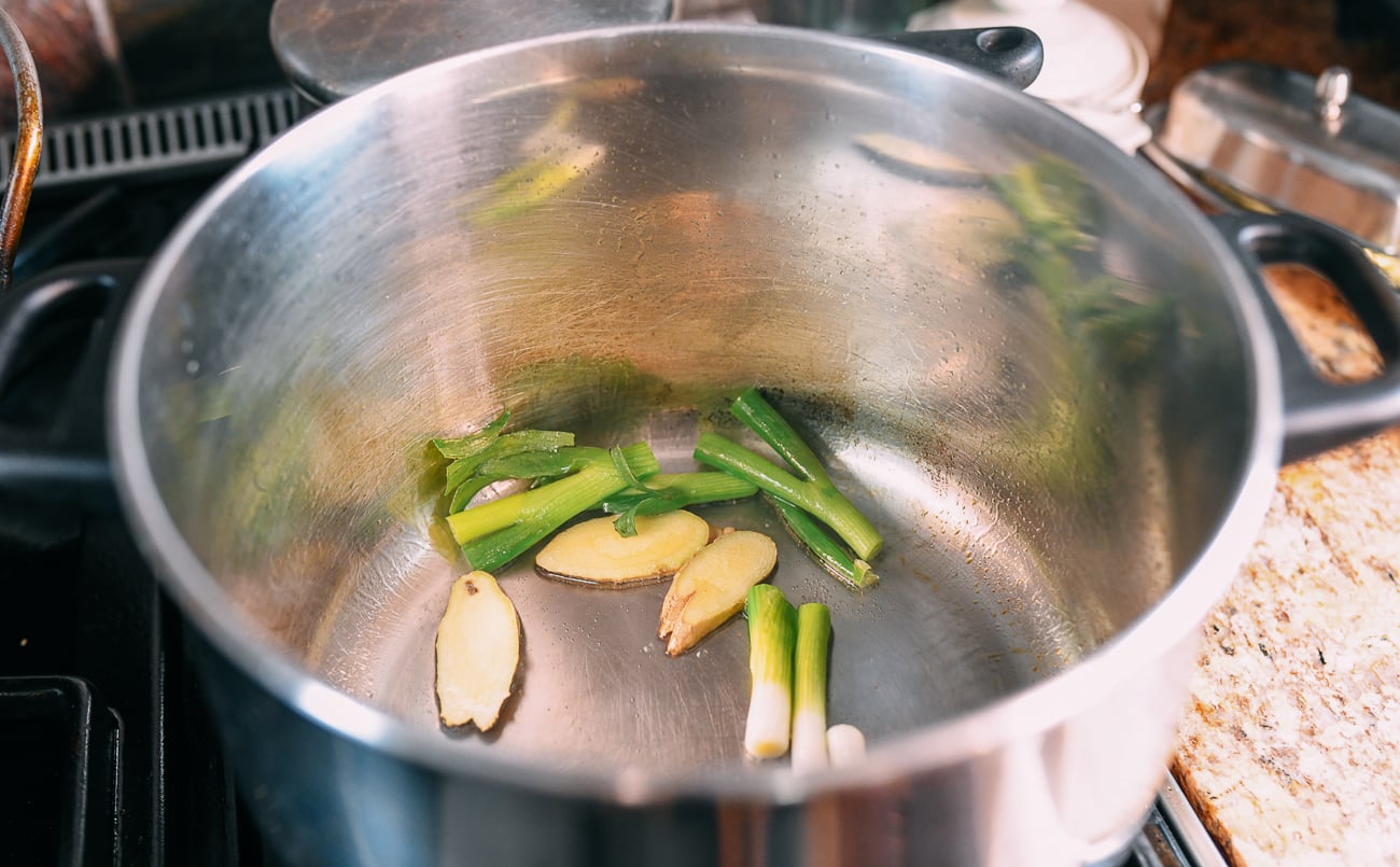 Oil, ginger slices, and white parts of scallions on pot