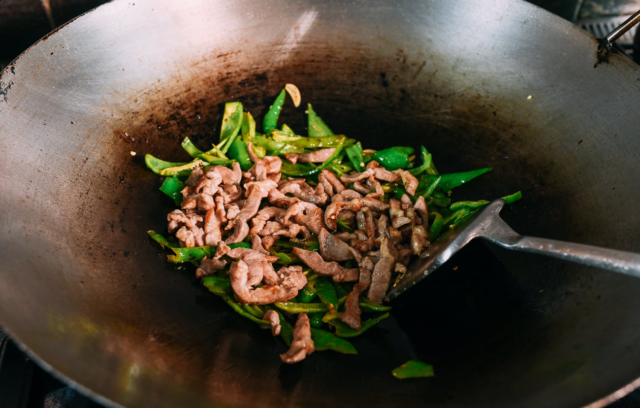 Pork added to peppers in wok