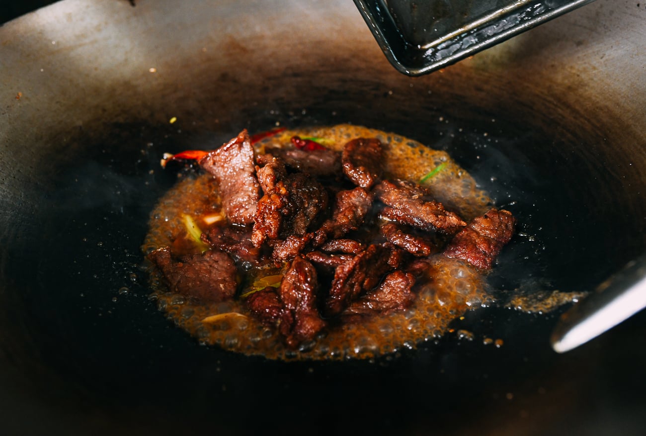 Adding beef to orange sauce in wok