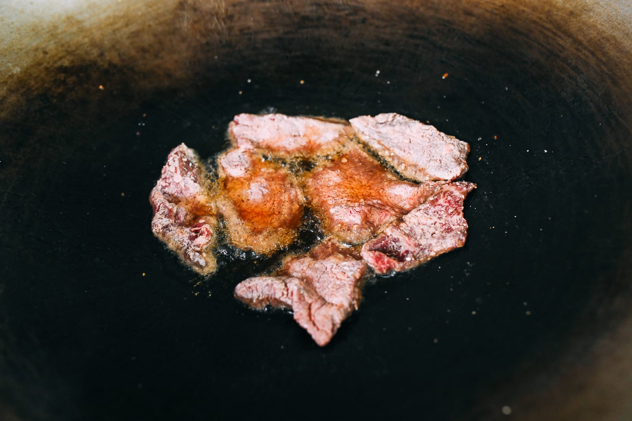 Dredged beef slices frying in oil in wok