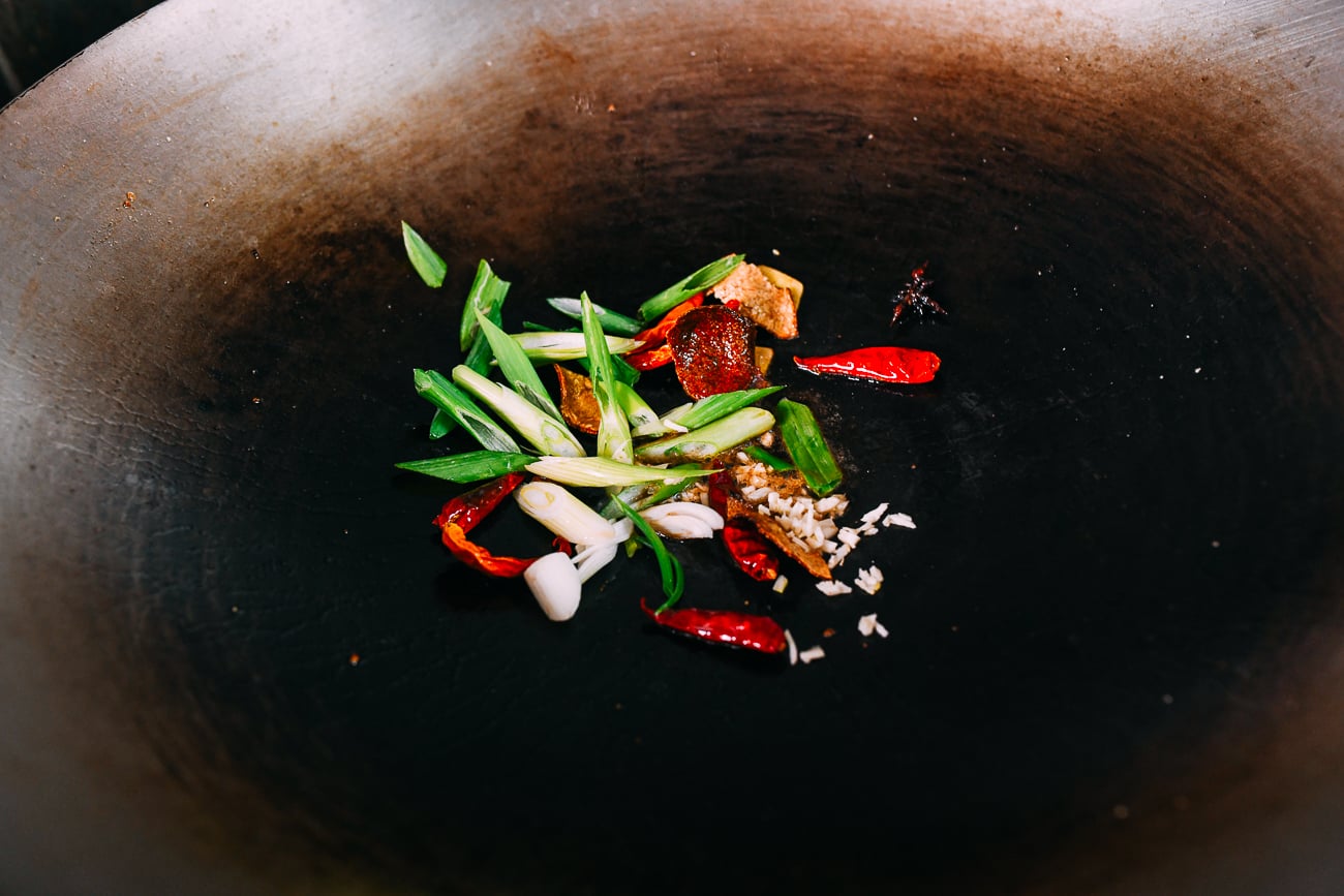 Scallions, garlic, ginger, dried chilies, dried orange peel, and star anise in wok