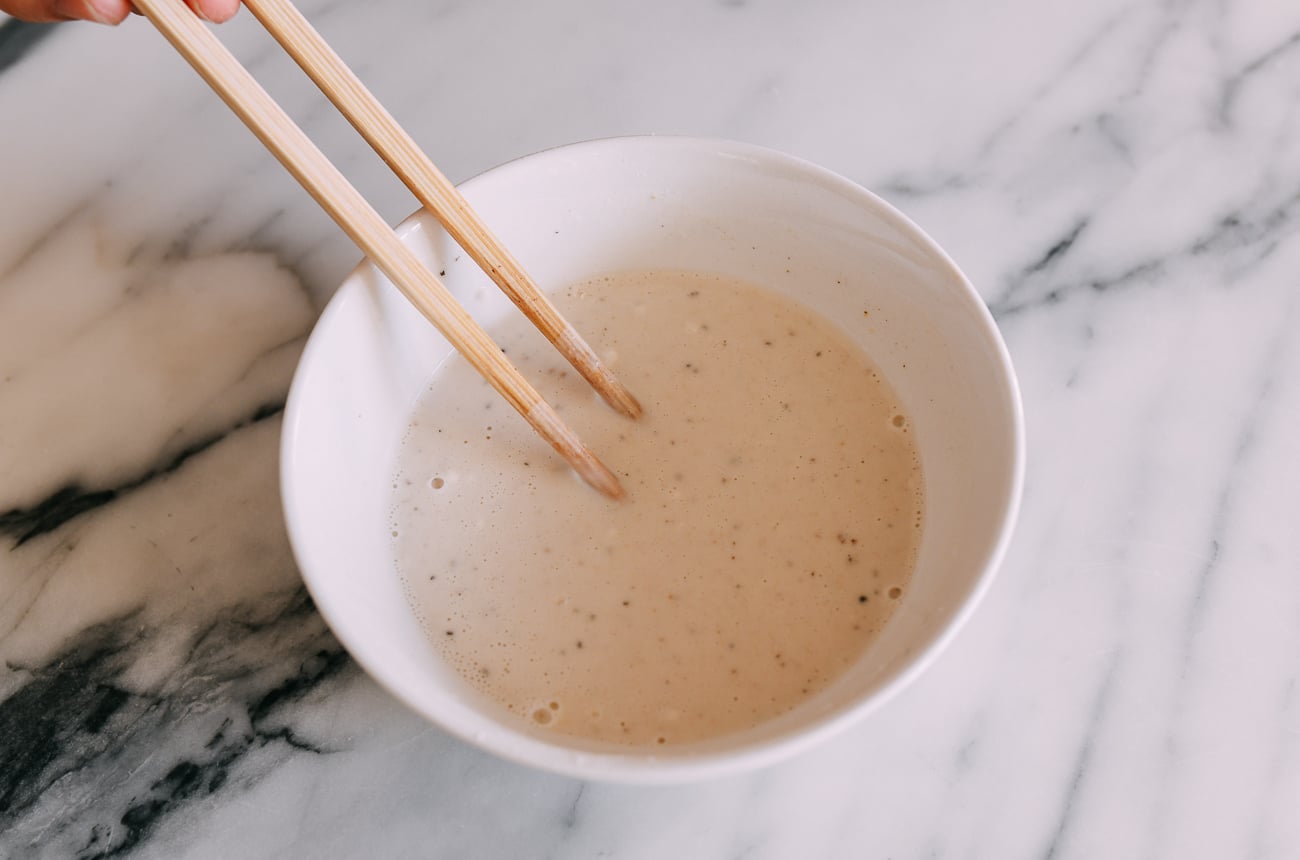 Stirring batter mixture with chopsticks in white bowl