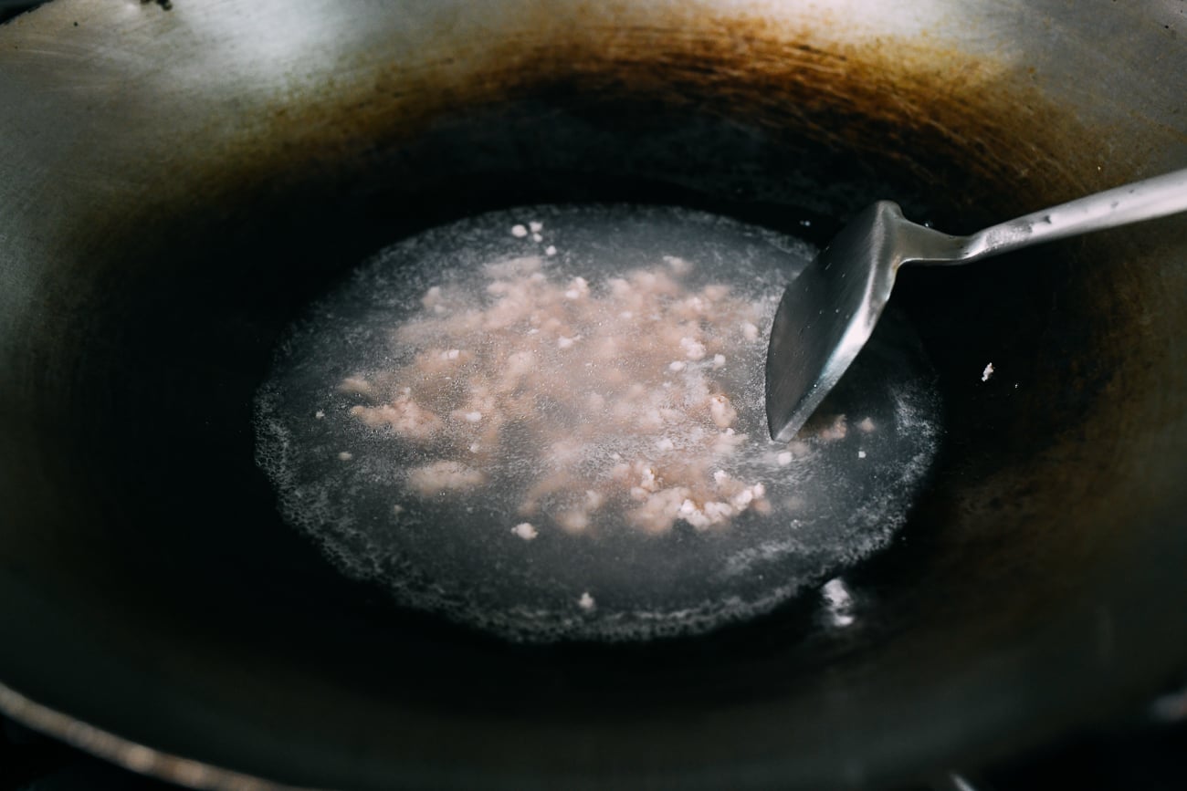 Blanching ground pork in a wok