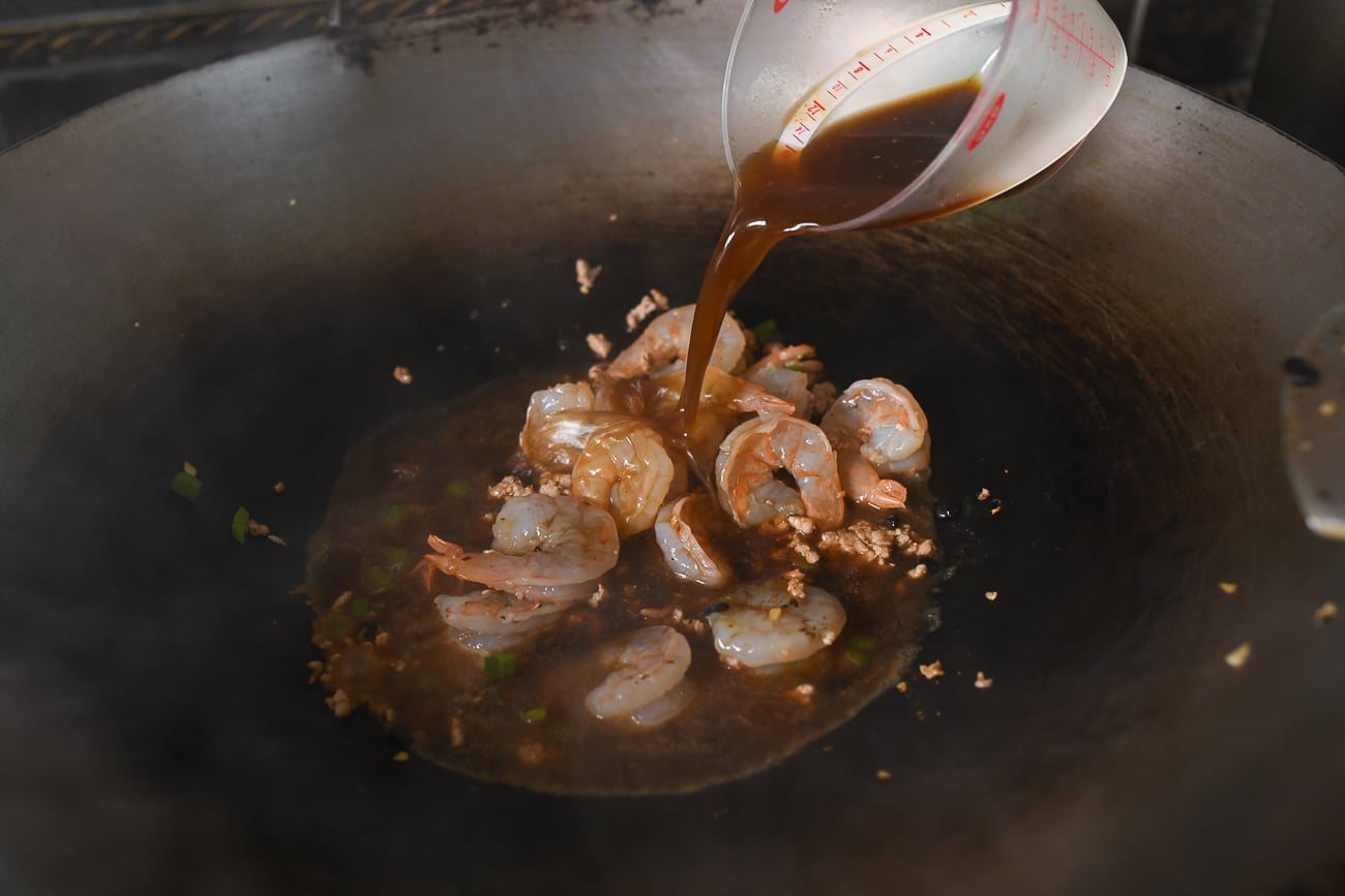 Pouring sauce mixture into wok with shrimp