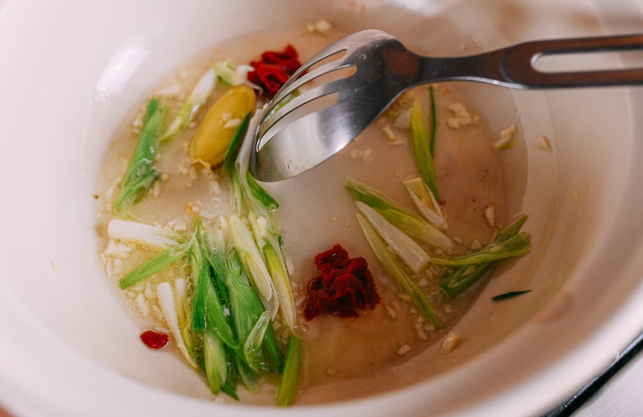 Cooking tomato paste, garlic, scallions, and ginger