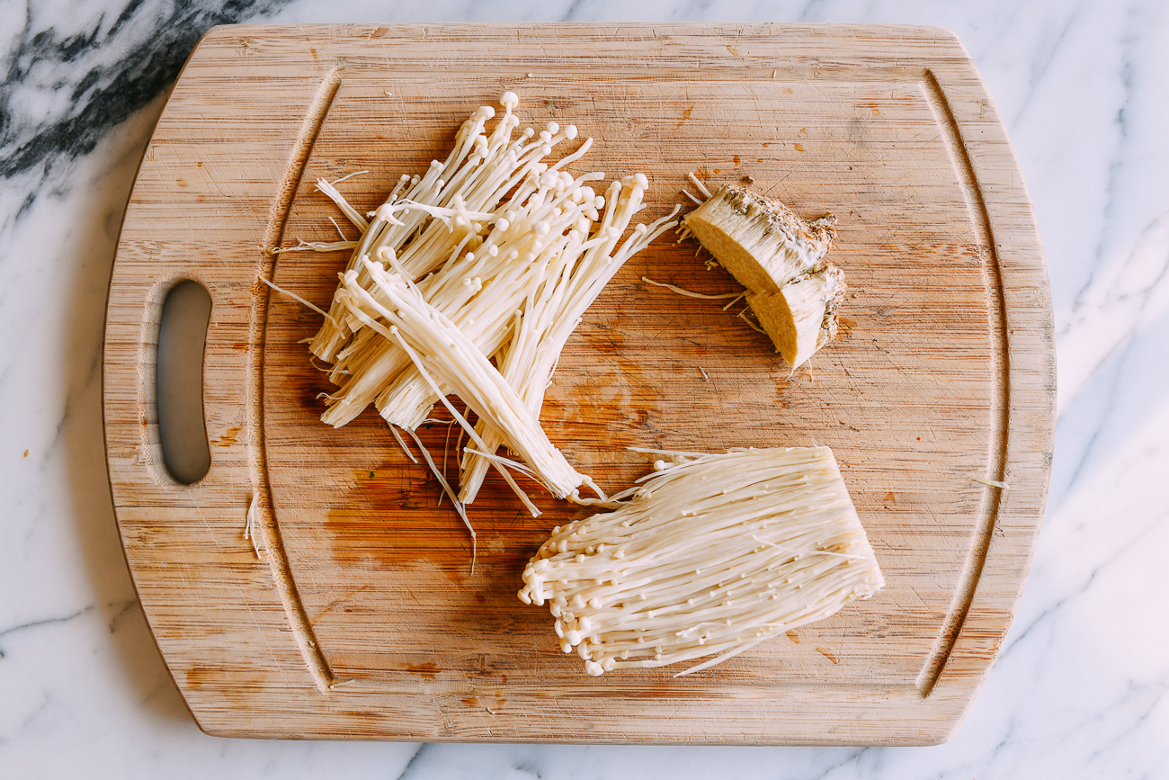 Preparing enoki mushrooms on cutting board
