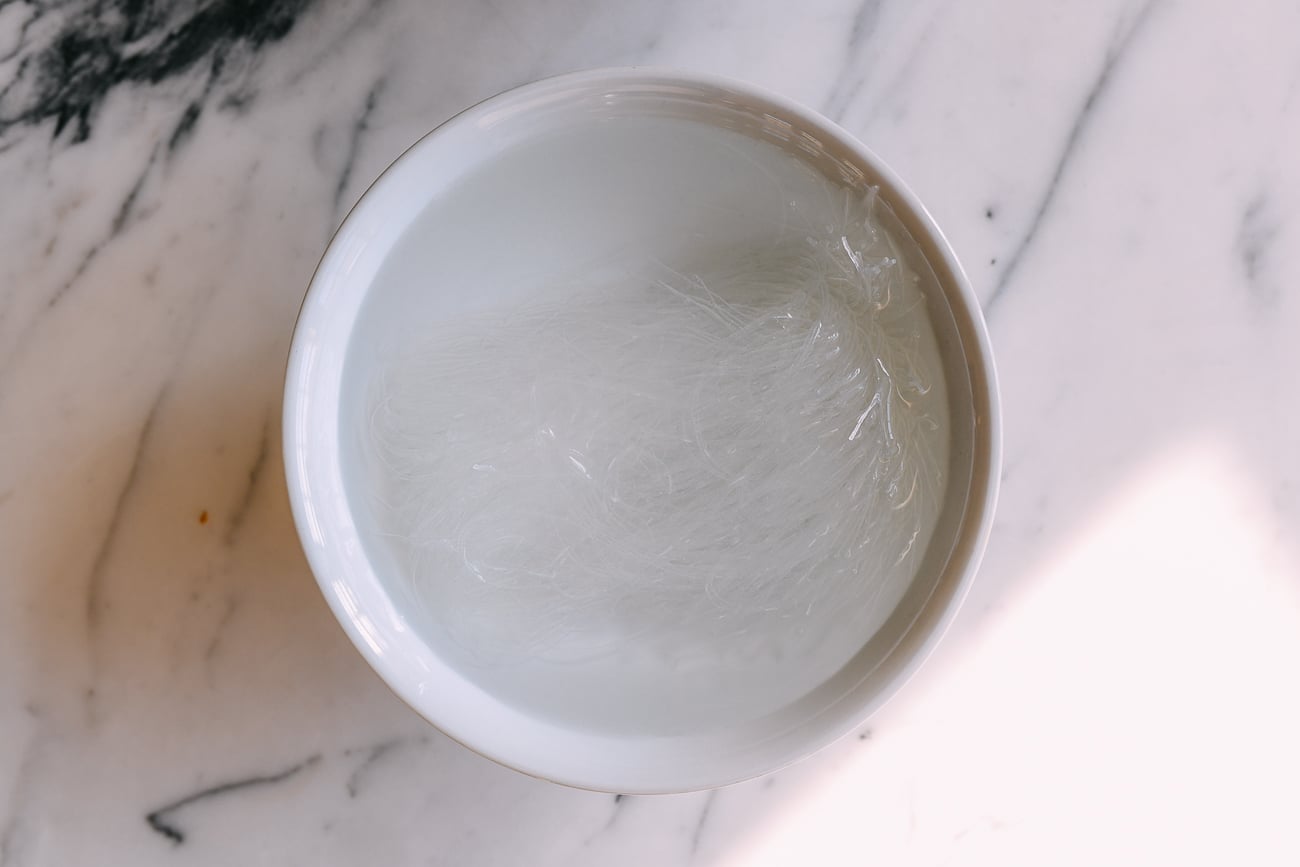 Mung bean vermicelli noodles soaking in water in a white bowl