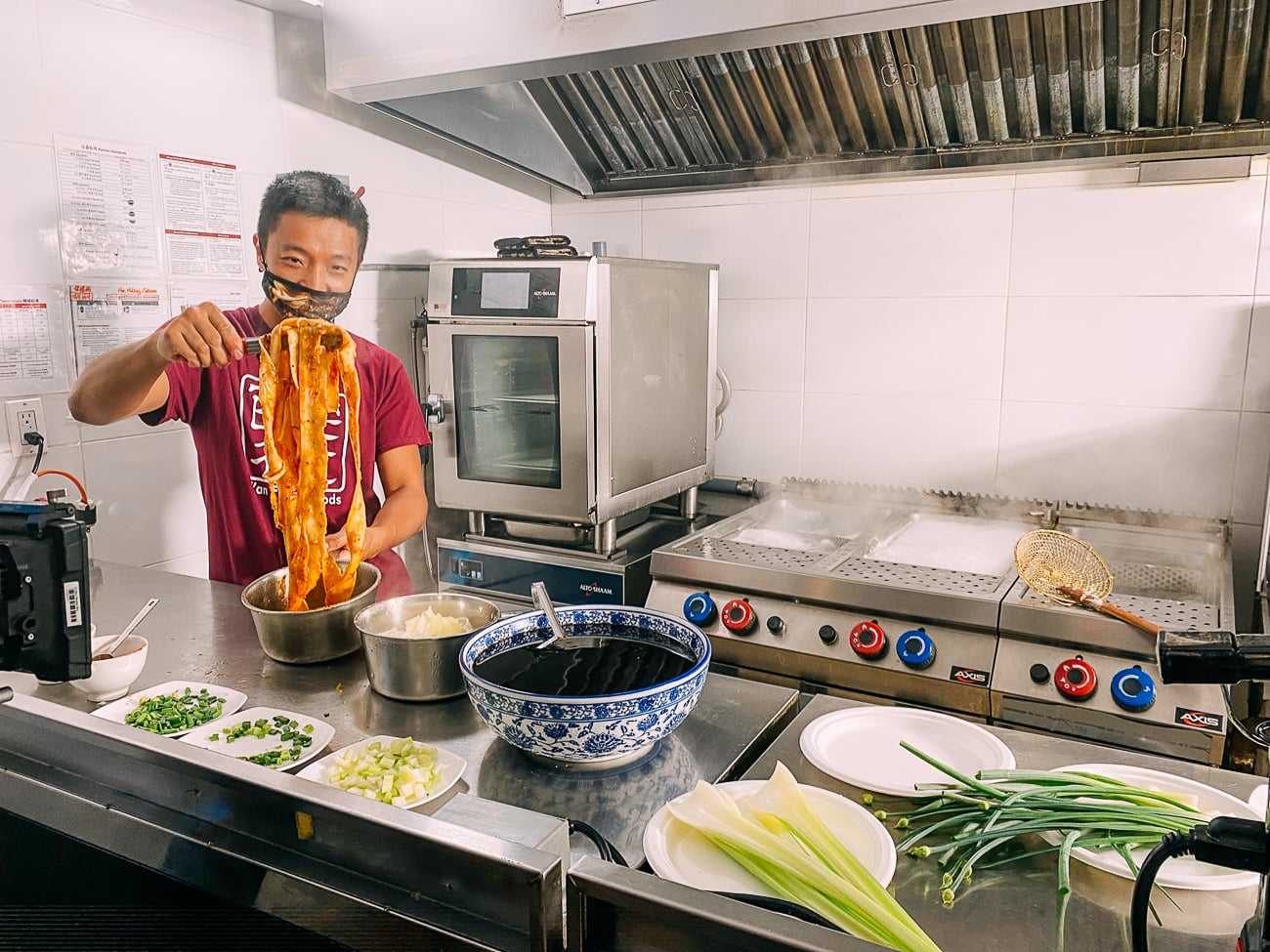 CEO and Owner of Xi'an Famous Foods, Jason Wang, preparing hot oil seared noodles