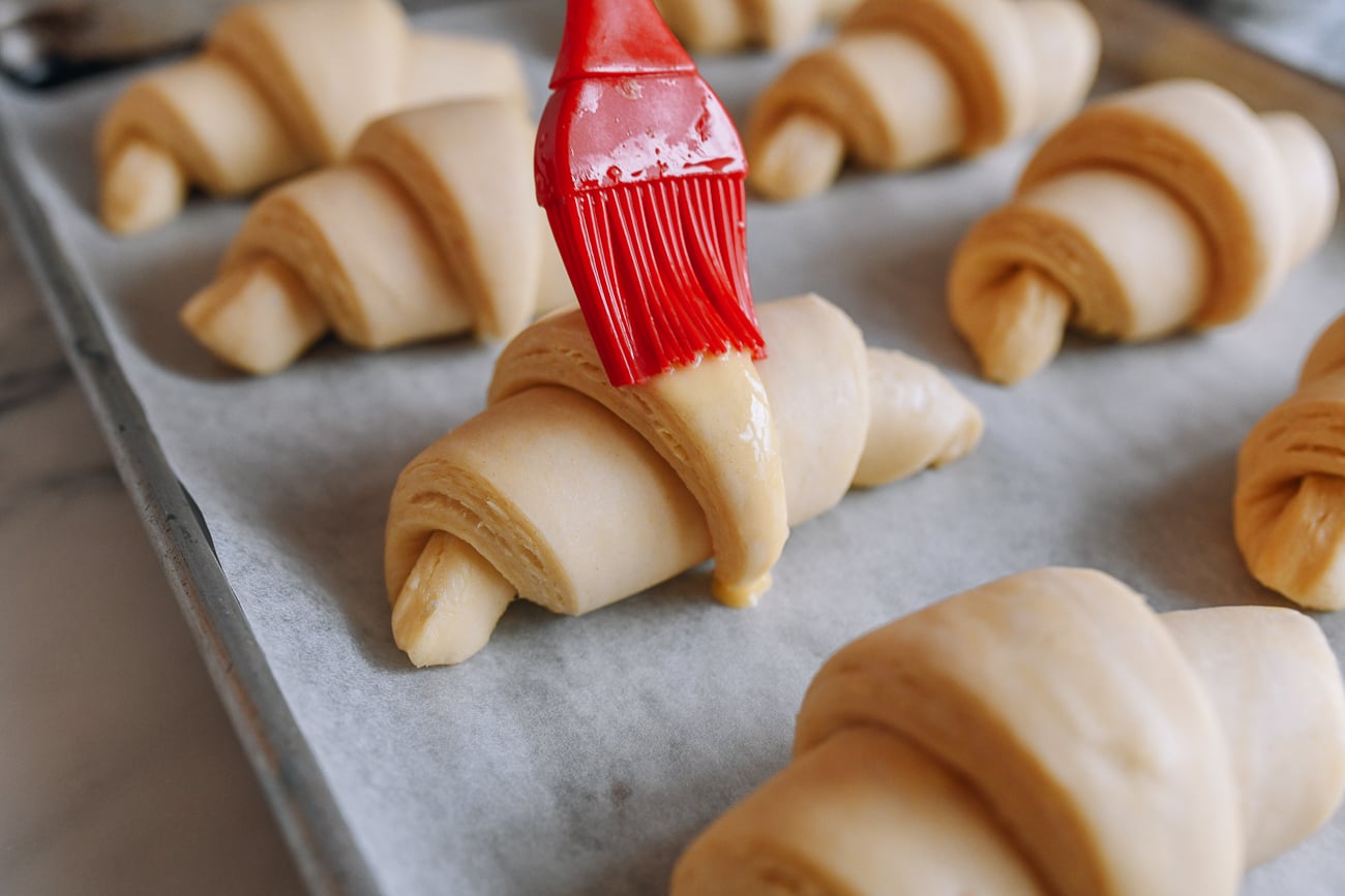 Brushing egg wash onto unbaked croissants