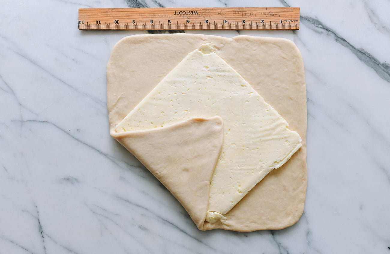 Folding dough around square of butter