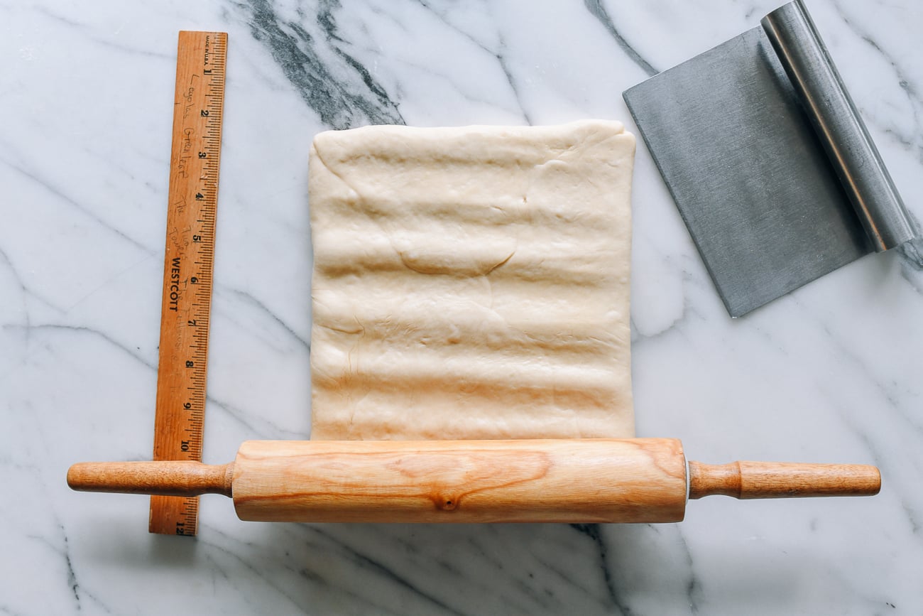 Pressing rolling pin into dough to flatten it