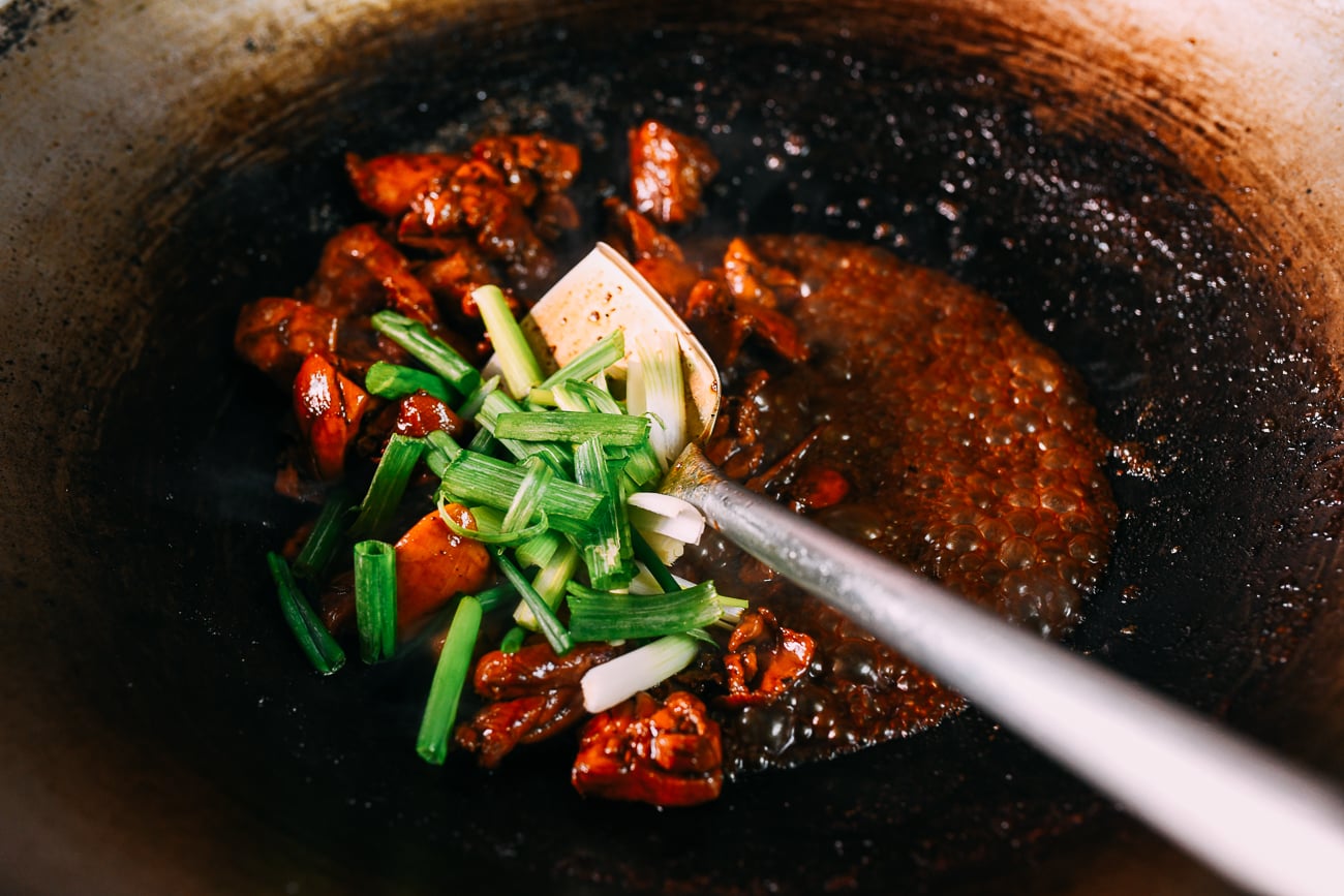 Mixing scallions into braised chicken