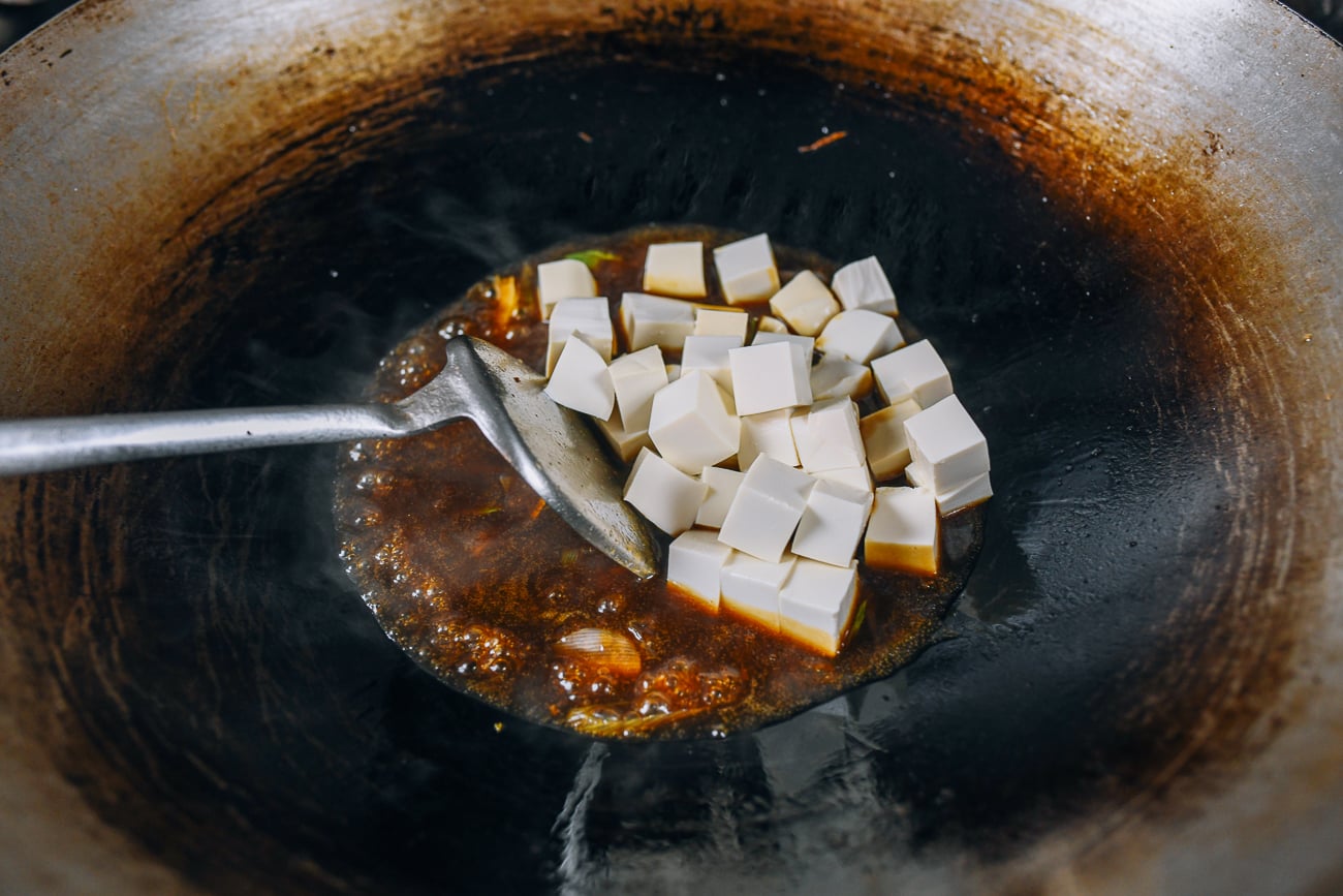 Adding tofu to sauce mixture in wok