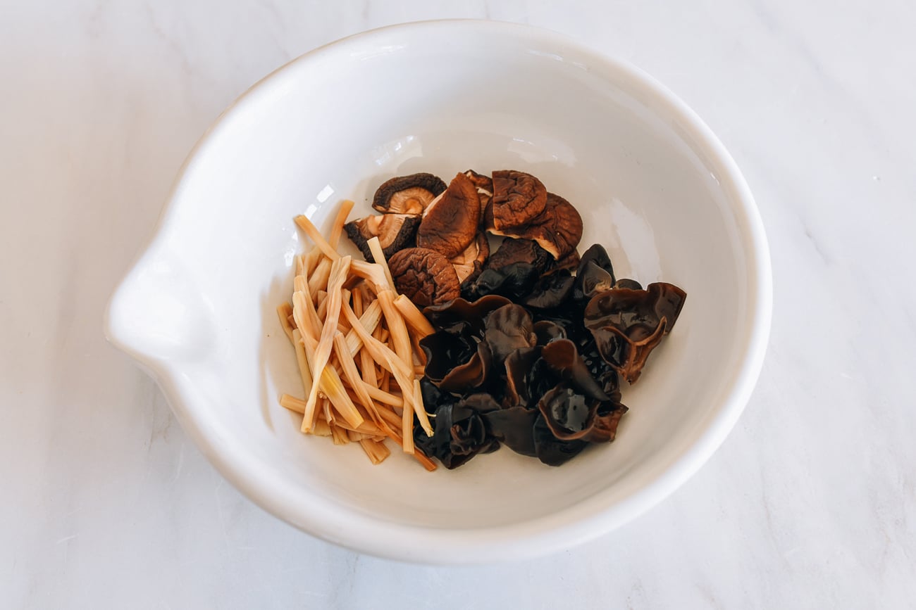 Rehydrated lily flowers, shiitake mushrooms, and wood ears in white bowl