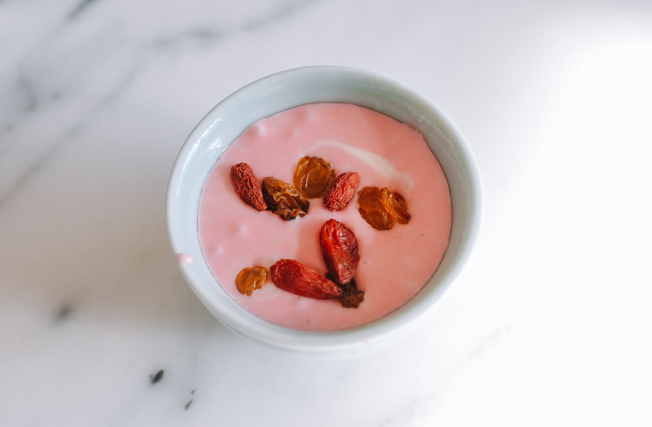fa gao batter in tea cup with dried goji berries and raisins on top