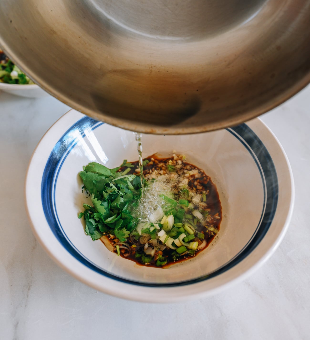 Pouring oil onto aromatics in heatproof bowl