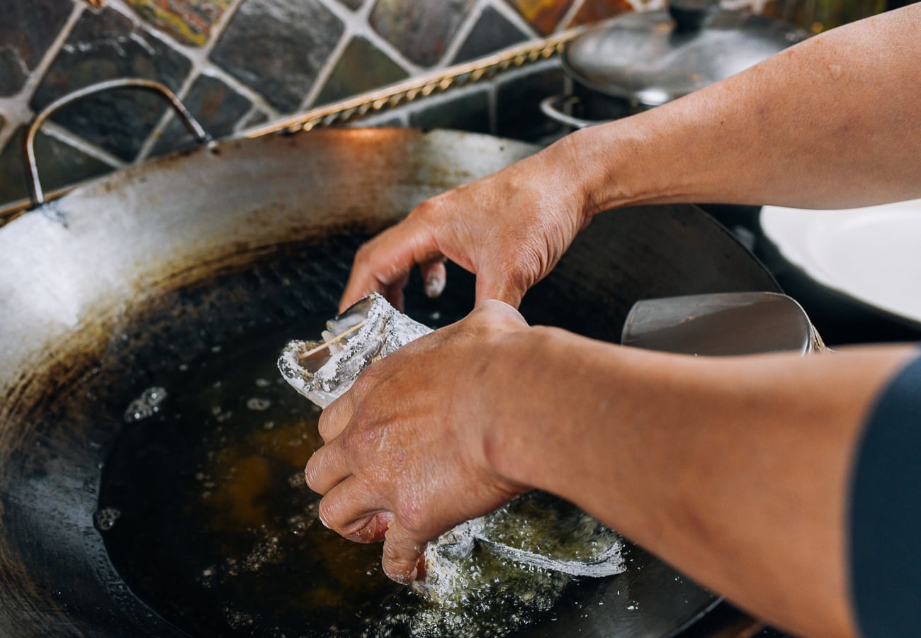 Laying fish head into hot frying oil