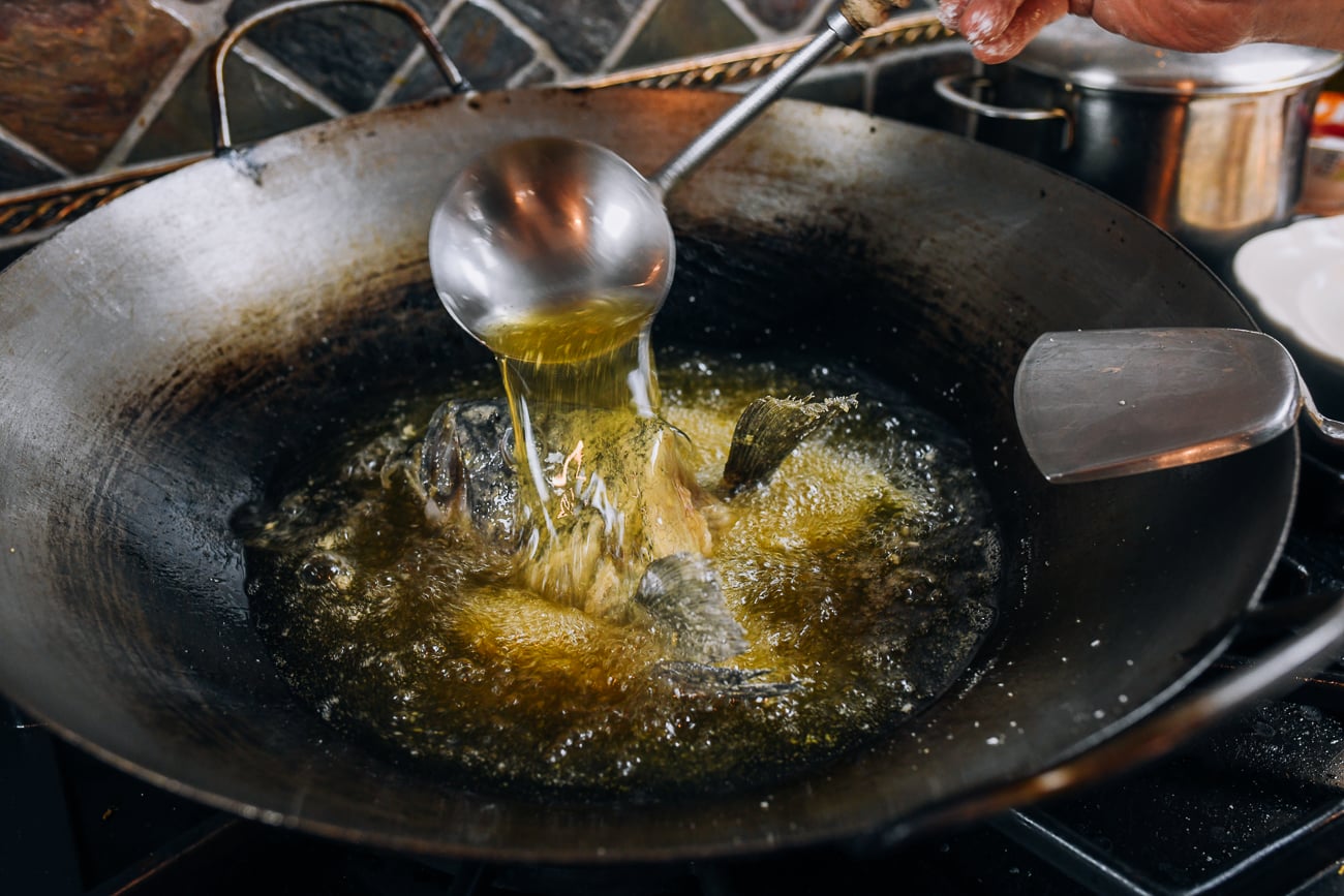 Ladling hot oil over fish head