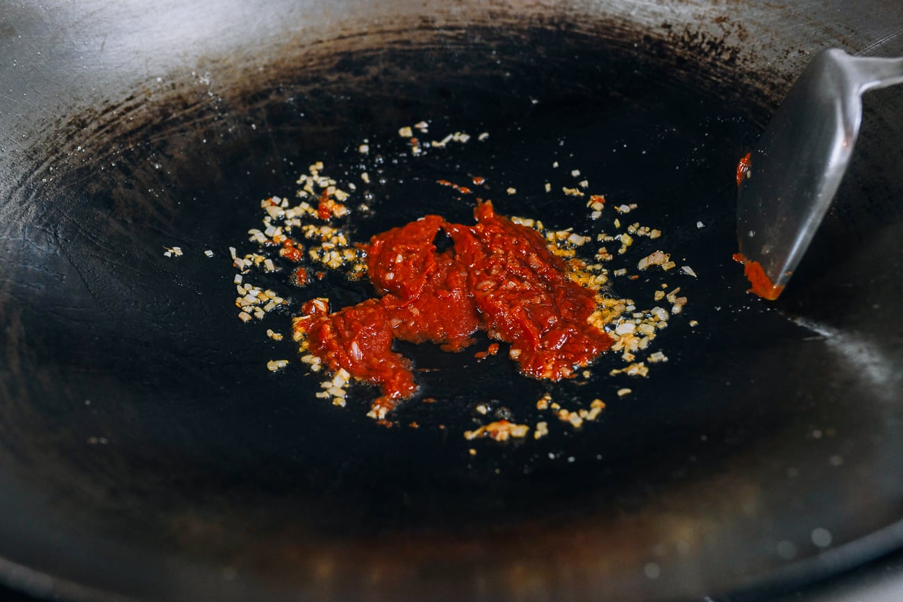 Adding tomato mixture to onions in wok
