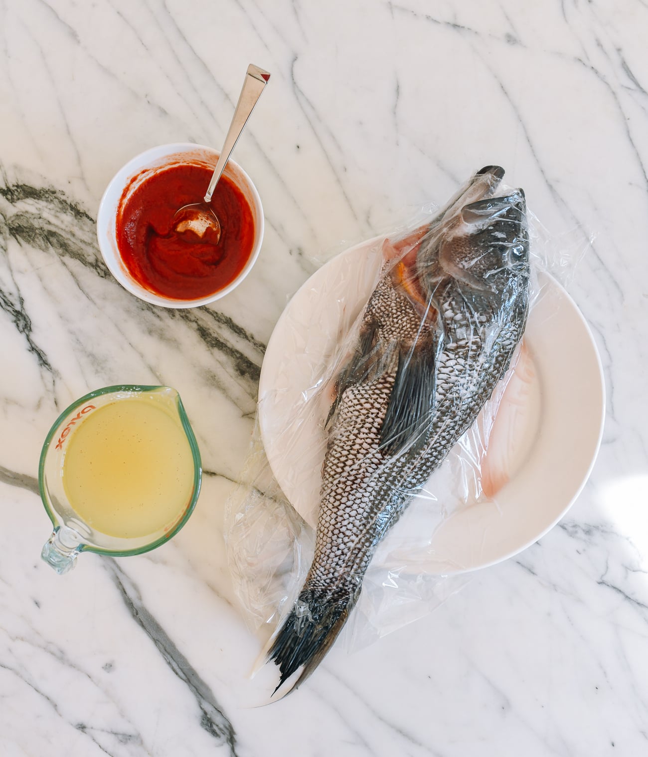 Vinegar mixture, tomato mixture, and cleaned sea bass on a plate