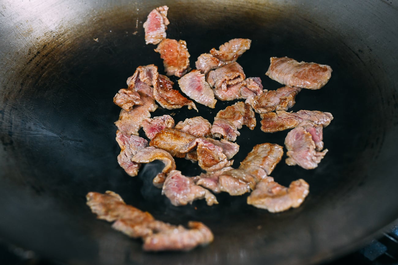 searing sliced beef in wok