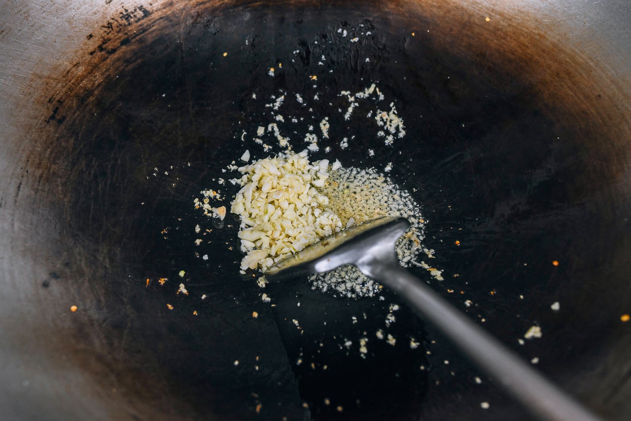 adding garlic to ginger in wok