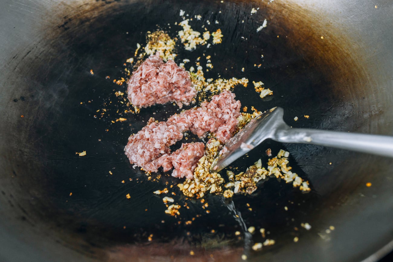 adding ground pork to wok