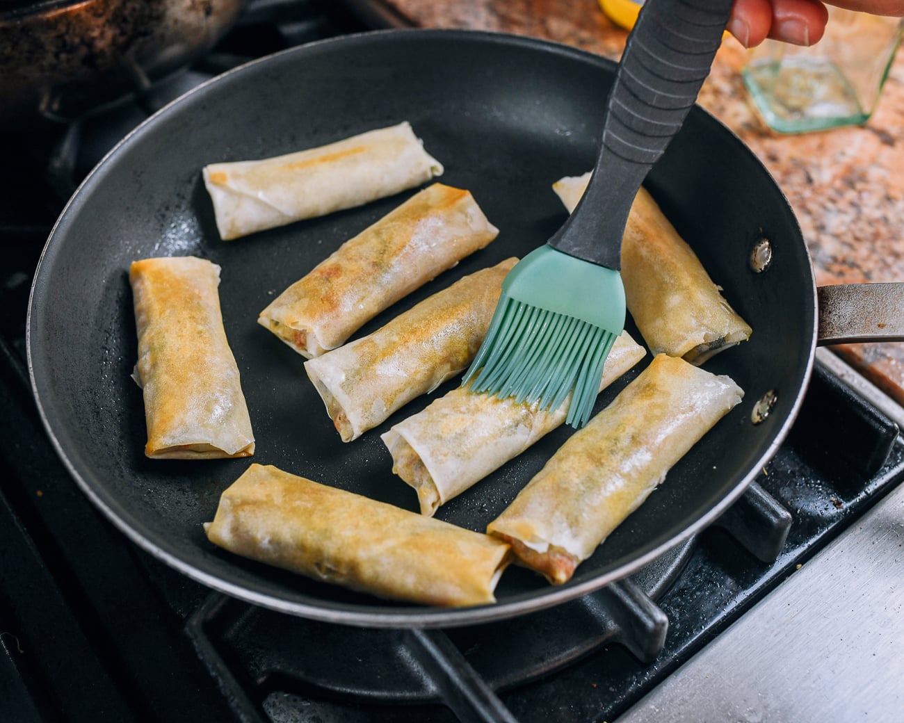 brushing pan-fried spring rolls with oil
