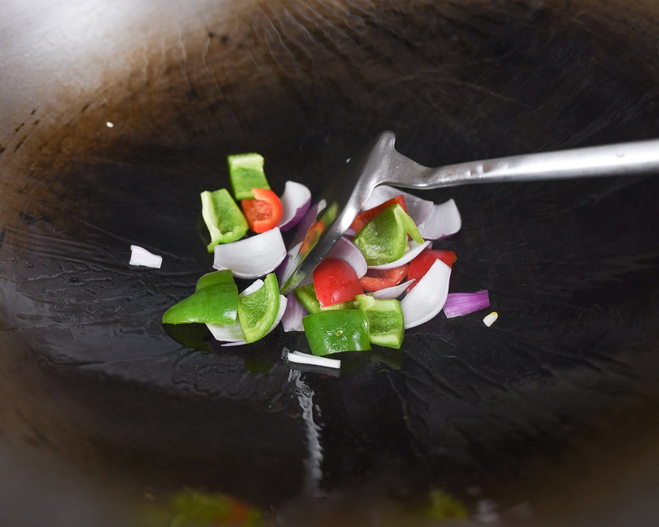 red onion and bell peppers in wok