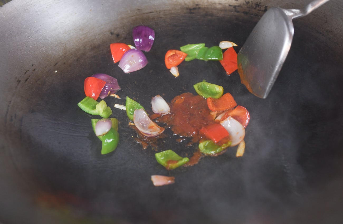 Ketchup in wok with vegetables to make sweet and sour sauce