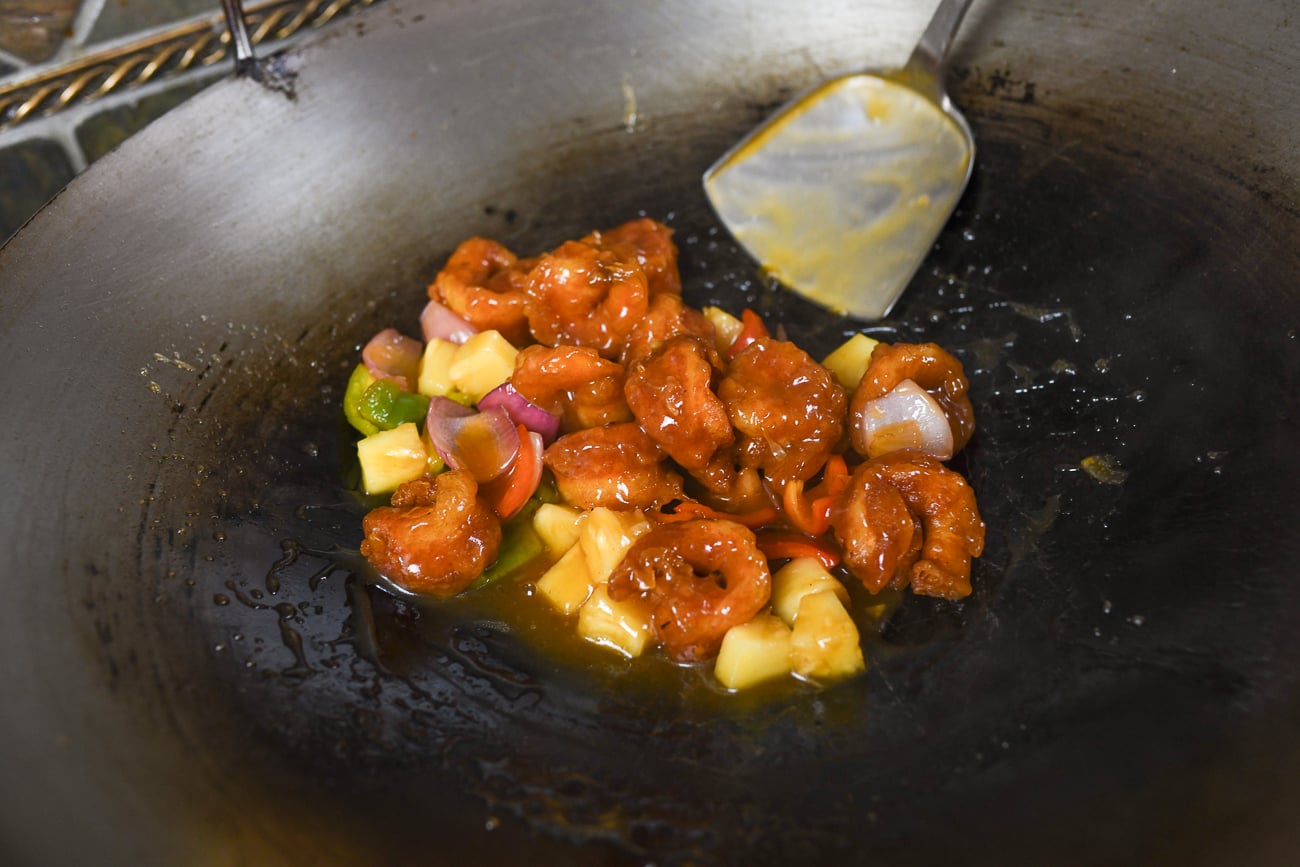 Tossing sweet and sour shrimp in wok