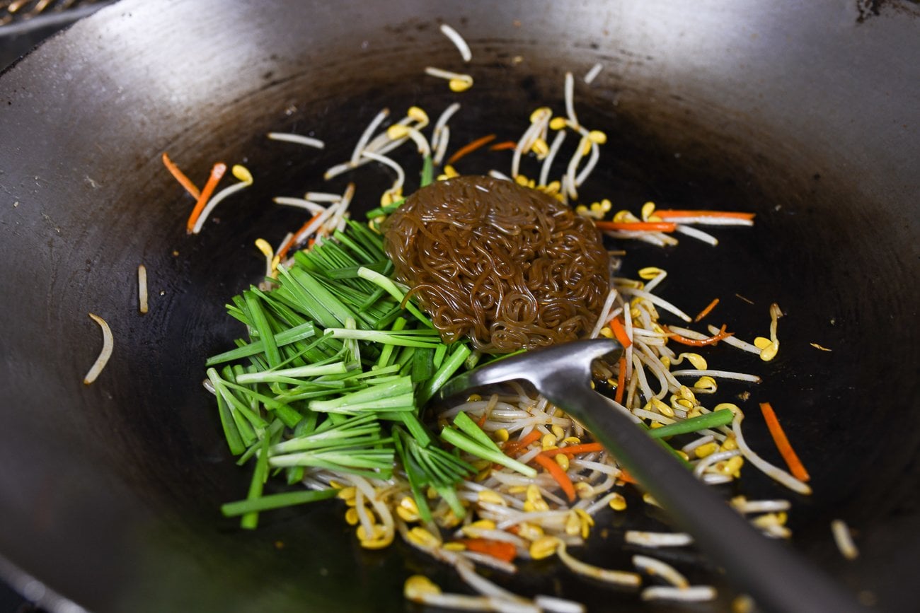 adding garlic chives to stir-fry