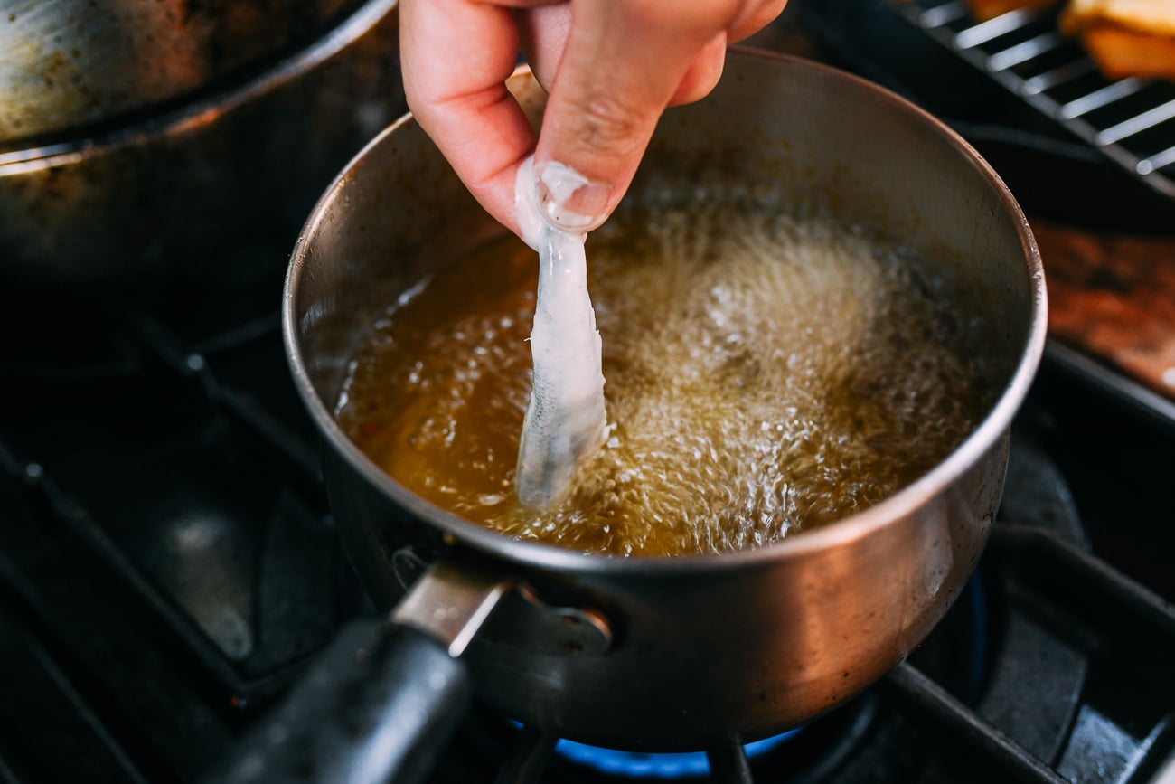 dipping battered smelt into frying oil