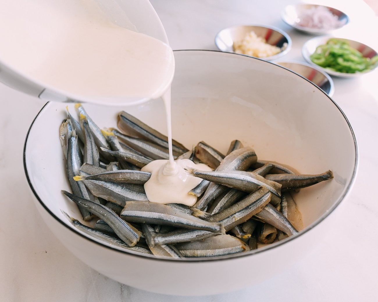 pouring batter on smelts in large bowl