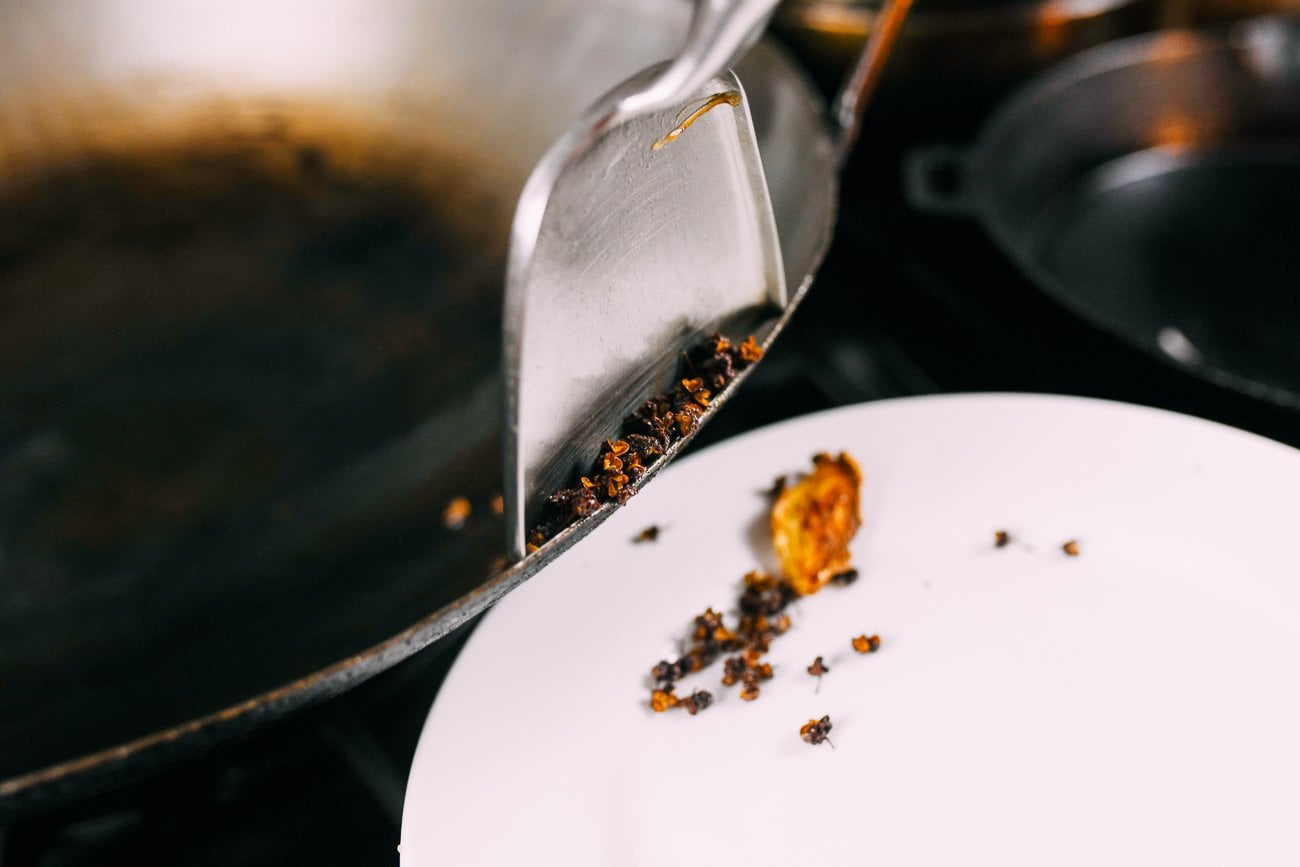 removing ginger and sichuan peppercorns from wok