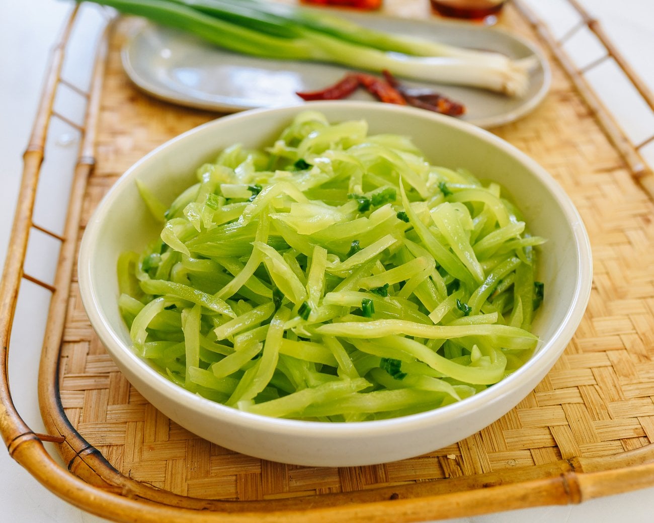 Shallow bowl of julienned celtuce with scallion oil