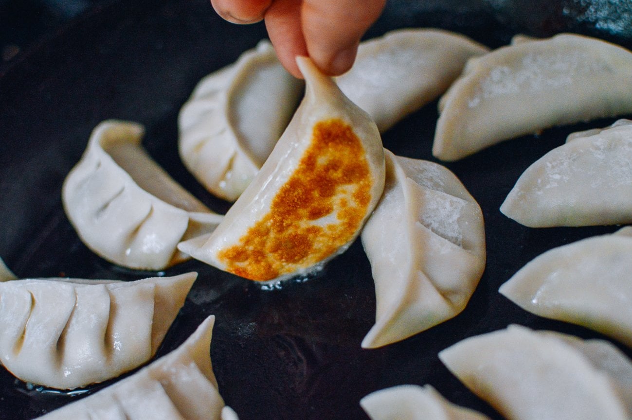 lifting dumpling in pan to show golden brown bottom
