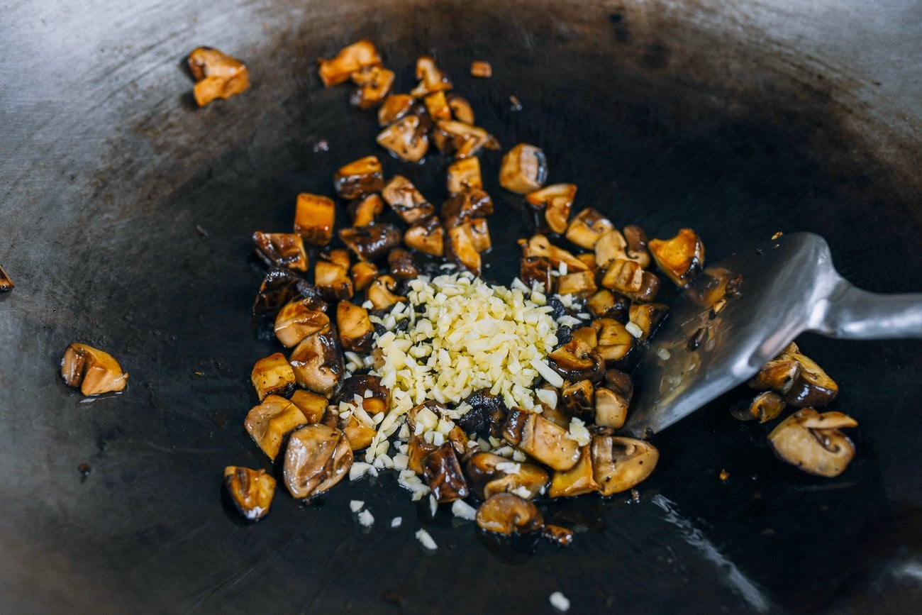 adding garlic and black beans to mushrooms