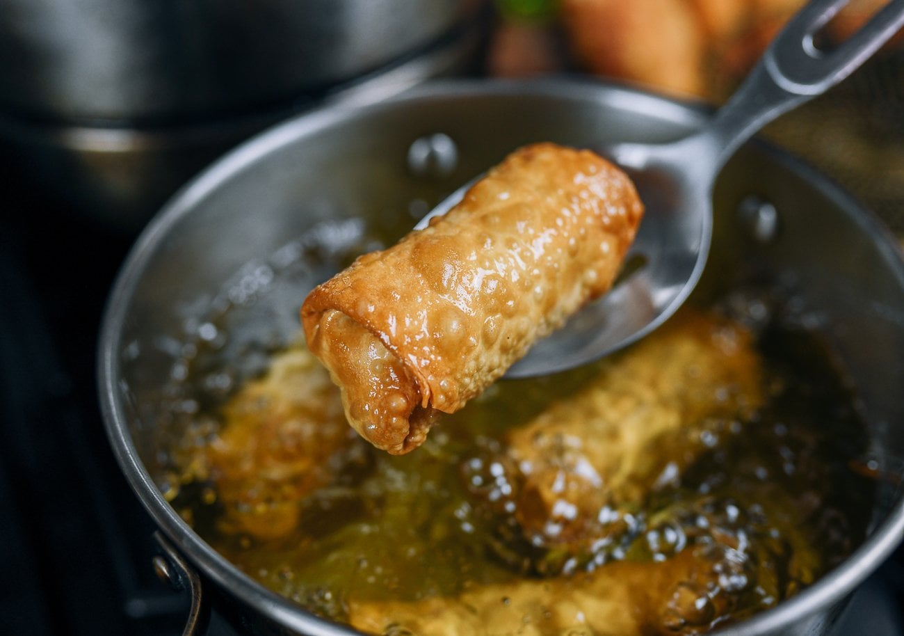 lifting fried egg roll with slotted spoon