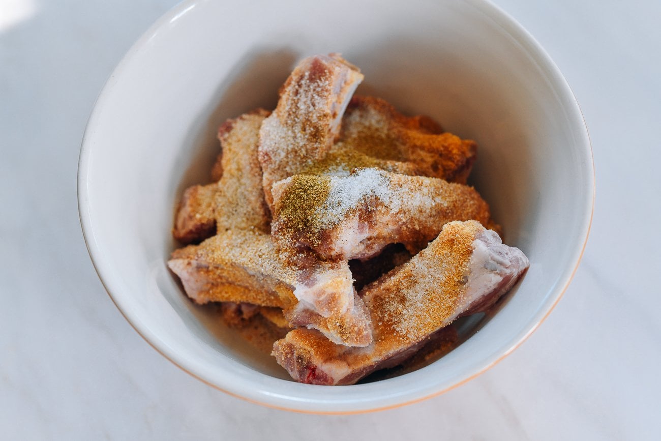 spices on ribs in mixing bowl