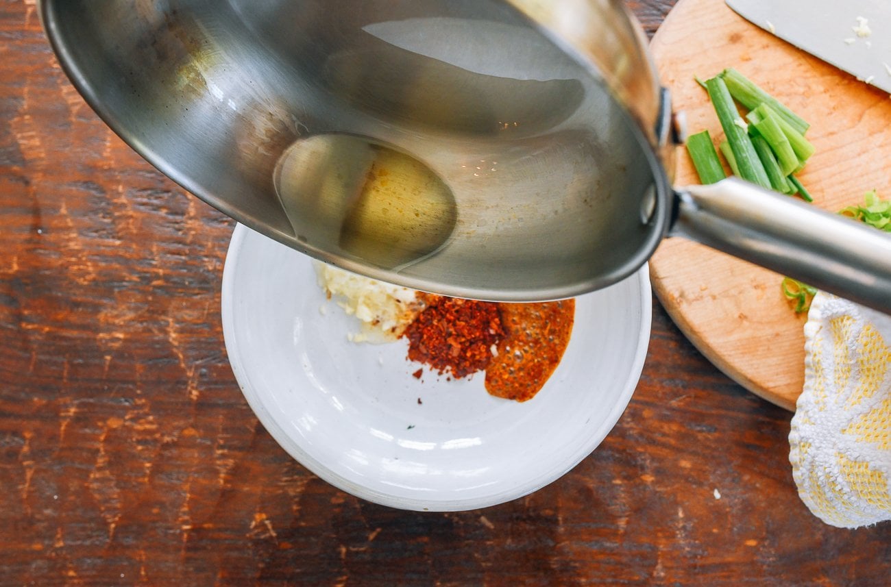 pouring hot oil over chili flakes and garlic