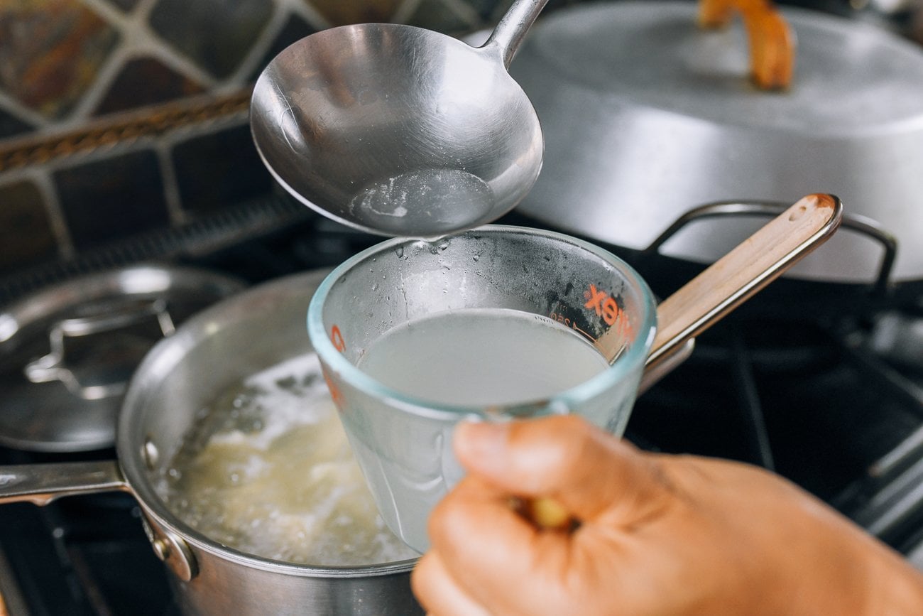 Ladling boiling water out of pot and into glass measuring cup