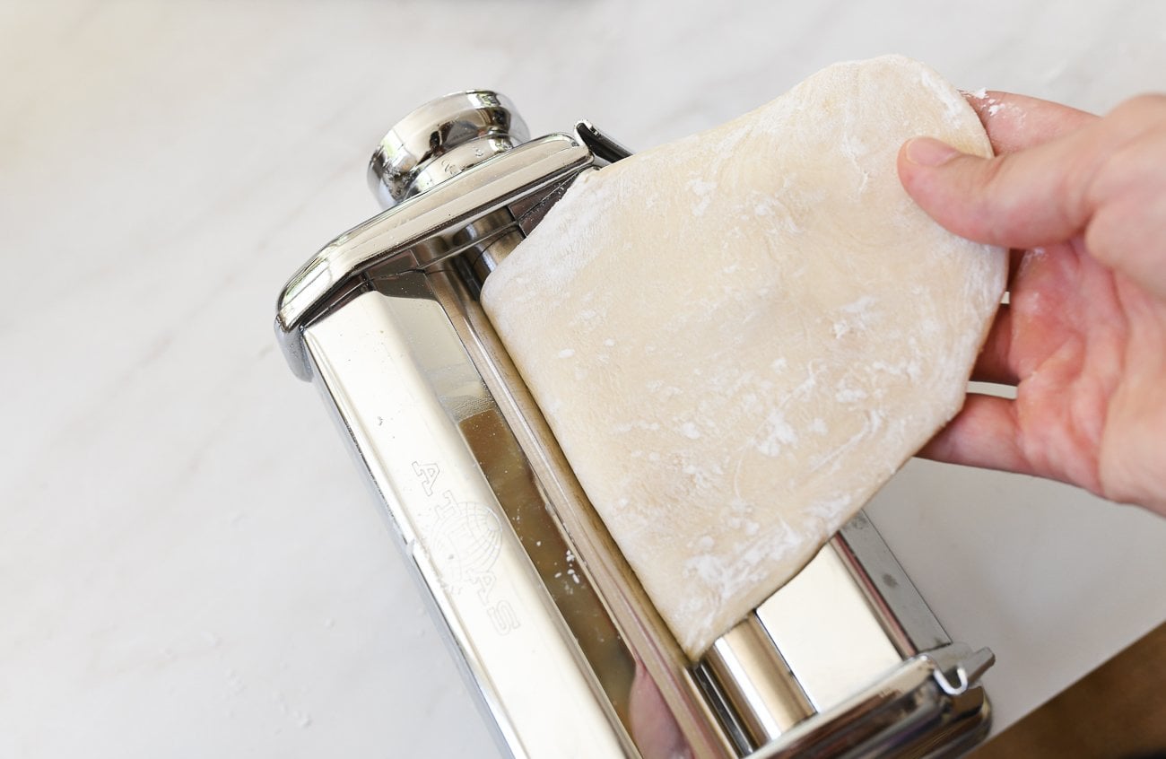 putting dough through pasta roller