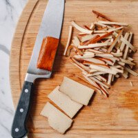 slicing pressed tofu or doufugan on cutting board