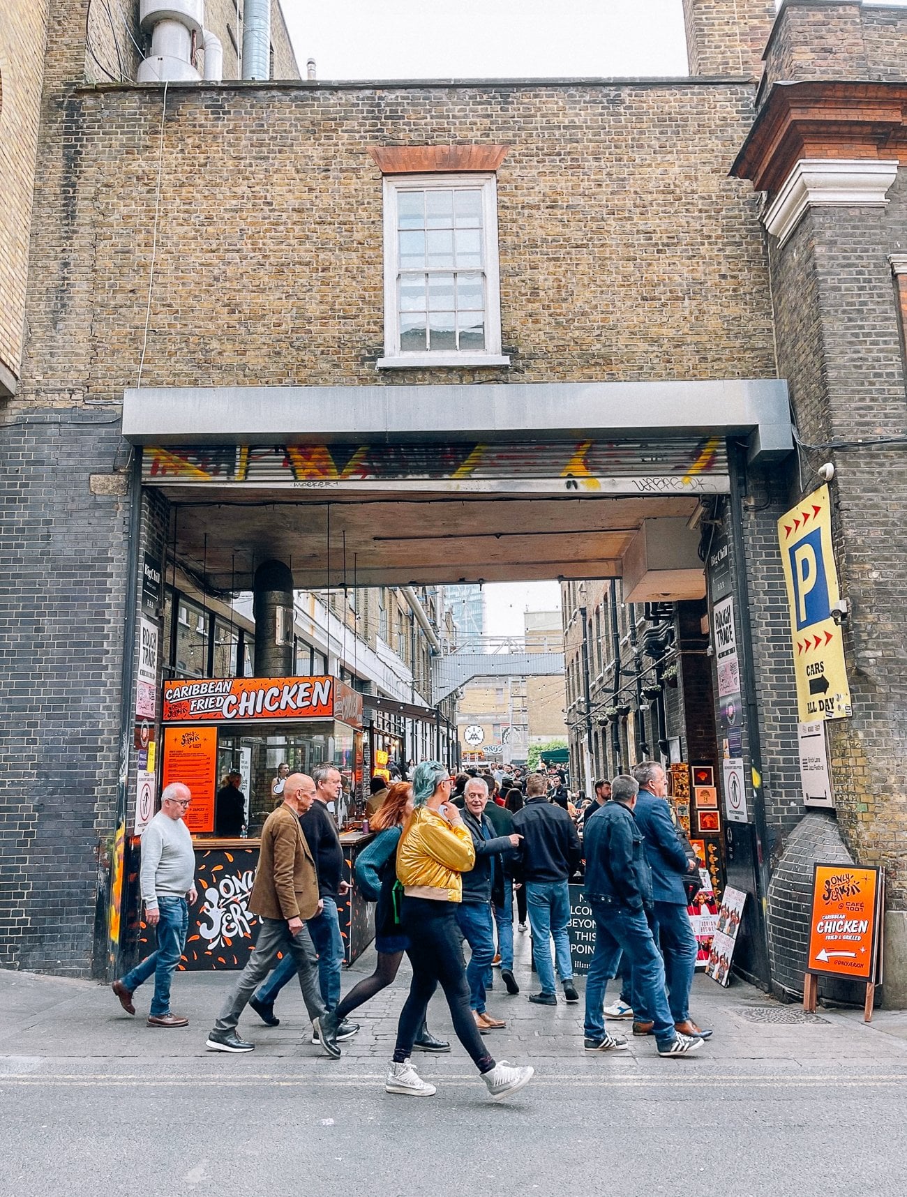 Crowded Shoreditch alleyway with a girl with blue hair and a gold jacket