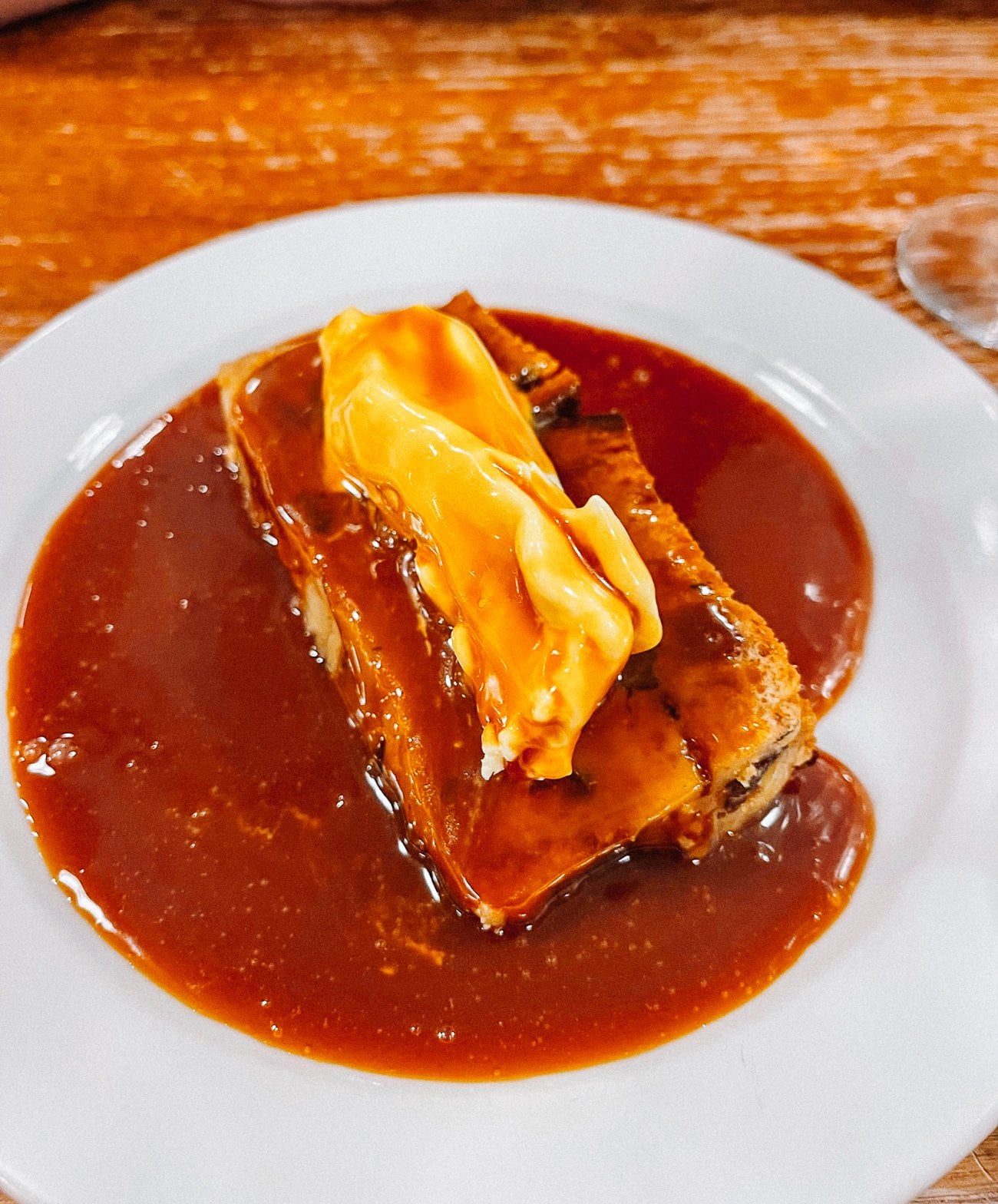 Bread pudding with clotted cream topped with a pool of toffee sauce