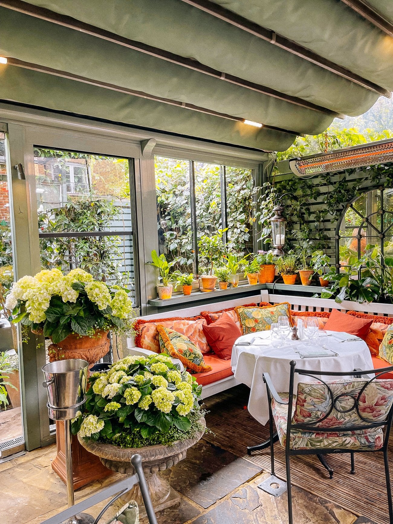 The Ivy Chelsea Gardens outdoor seating with tablecloth and floral bench