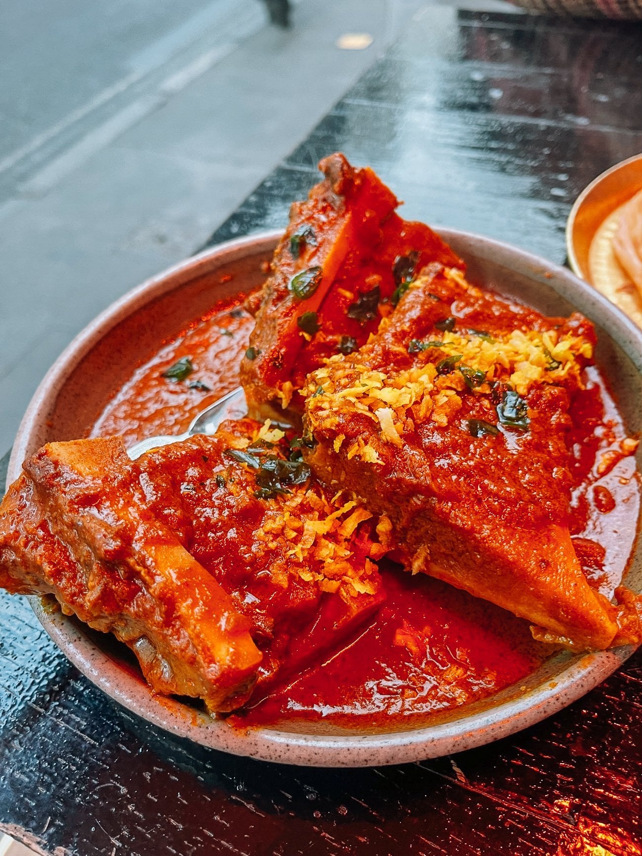 Plate of bone marrow varuval, two large pieces of bone marrow in a red curry